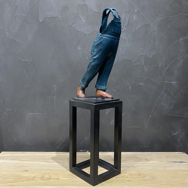 Sculpture en bronze patinée bleue, rouge et noire représentant la salopette de Michel Colucci. La sculpture est faite de façon a donner l'impression que la célèbre comique est dans son costume de scène alors que la sculpture ne représenta ni sa tête ni le haut de son corps avec les bras.